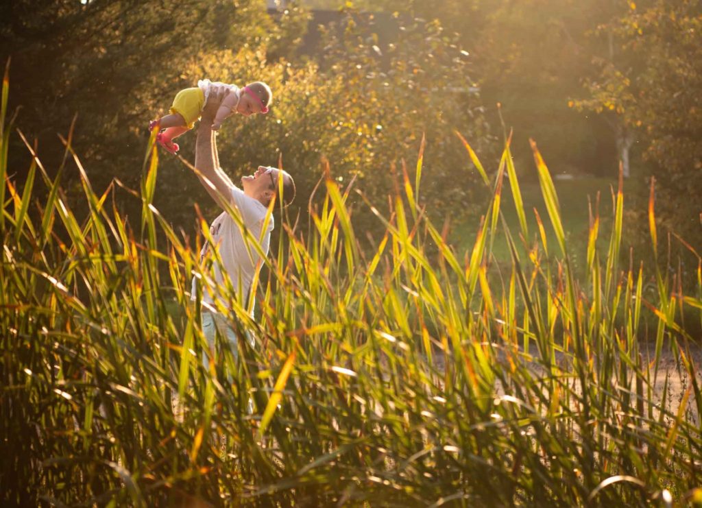 Dad lifting baby girl in the field