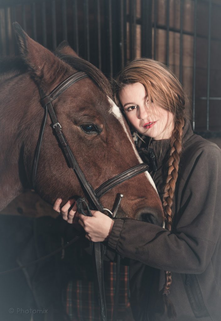 Model with her horse in a barn