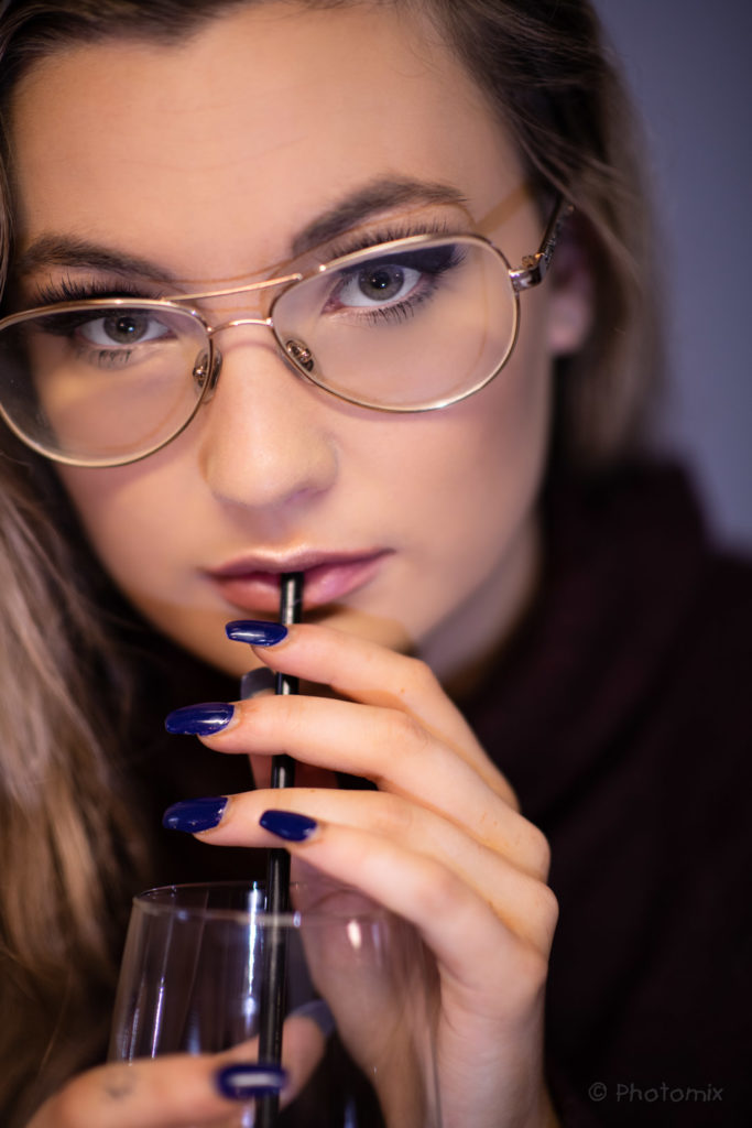Model with glasses drinking from a straw