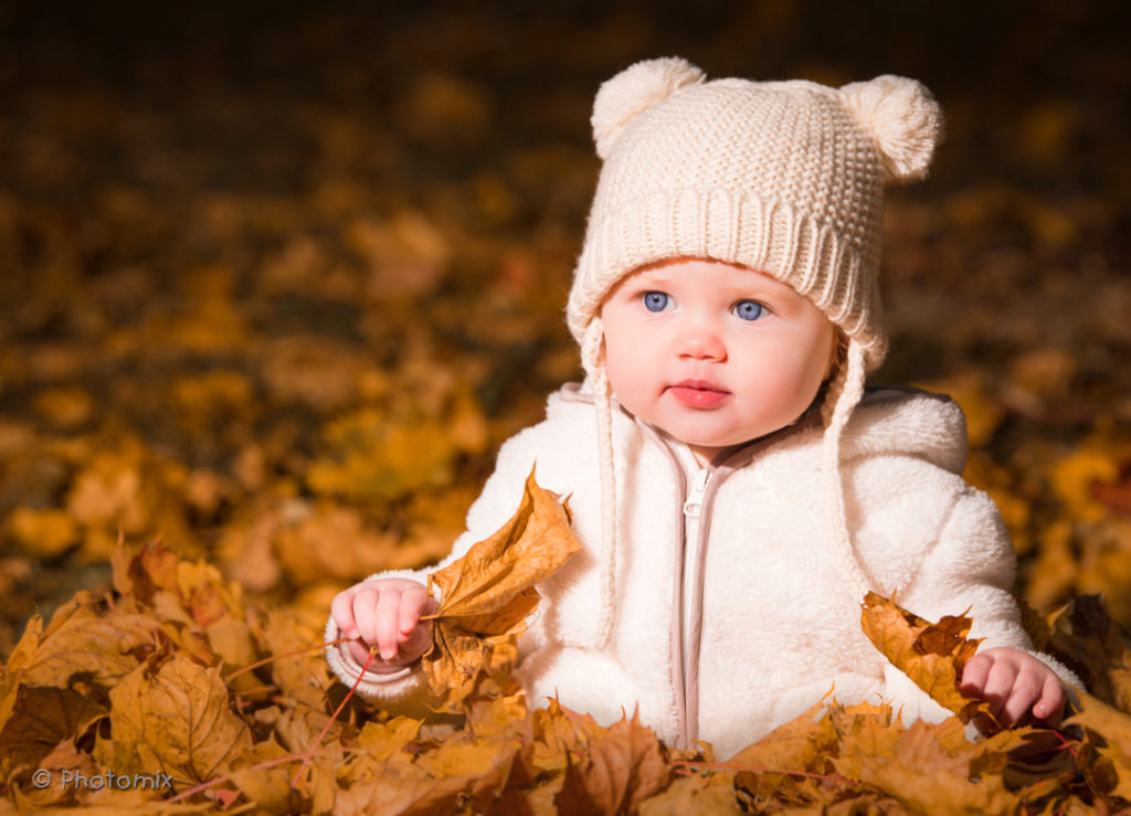Baby with blue eyes in fall leaves
